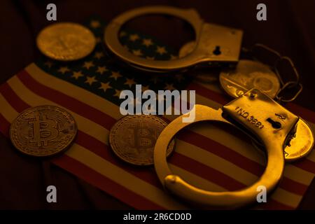 Golden Bitcoins Kryptowährung mit Handschellen auf Dollarscheinen. Konzept der digitalen Kriminalität, der Festnahme oder des Hacking. Handschellen Dollar und Bitcoins auf dem Tisch Stockfoto