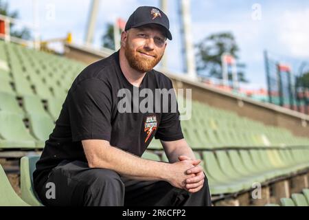 Berlin, Deutschland. 08. Juni 2023. American Football: Europäische Fußballliga, Media Day im Berliner Thunder, Friedrich-Ludwig-Jahn-Sportpark. Cheftrainer Johnny Schmuck vom Berliner Thunder sitzt auf einem Stand und lächelt. Kredit: Andreas Gora/dpa/Alamy Live News Stockfoto