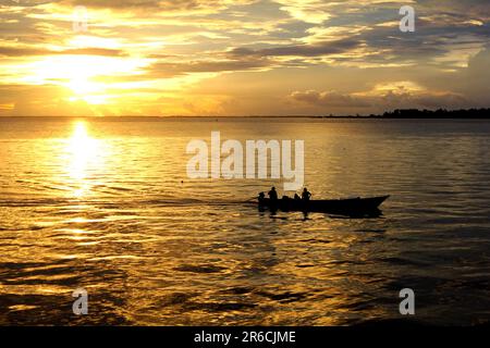 Erleben Sie die faszinierende Reise zweier Seelen, während sie durch das ruhige Wasser des Amazonas gleiten, umgeben von den lebendigen Farben eines Sonnenuntergangs Stockfoto