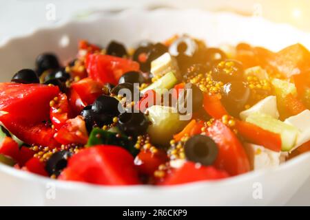 Nahaufnahme eines klassischen griechischen Salats. Mit saftigen Tomaten, knusprigen Gurken, rotem Pfeffer, Zwiebeln und geschmückt mit Oliven, Oregano und Fetakäse Stockfoto