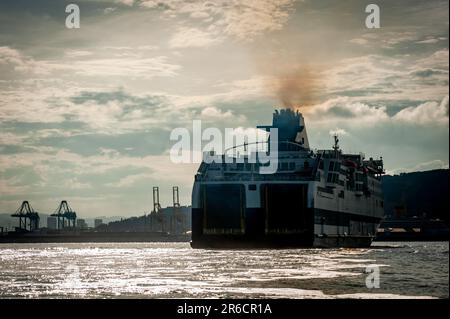 Die Schornsteine der Fähre geben Rauch ab, während sie den Hafen von Barcelona ansteuern. Schwefeldioxid- und Stickoxidemissionen machen den Hafen von Barcelona in Europa zum schlechtesten für die Luftverschmutzung. Stockfoto