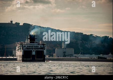 Die Schornsteine der Fähre geben Rauch ab, während sie den Hafen von Barcelona ansteuern. Schwefeldioxid- und Stickoxidemissionen machen den Hafen von Barcelona in Europa zum schlechtesten für die Luftverschmutzung. Stockfoto