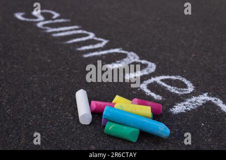 Farbige Kreide Nahaufnahme des Hintergrunds des Wortes Summer, gezeichnet mit weißer Kreide auf dem Bürgersteig. Stockfoto