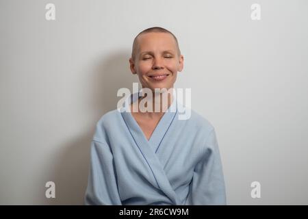 Porträt einer glatzköpfigen lächelnden Frau im Bademantel auf weißem Hintergrund. Frau mittleren Alters mit positivem Befund ohne Haare. Erholung nach Onkologie, Chemotherapie Stockfoto