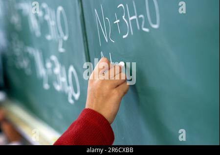 Schülerin, die einen Wissenschaftsauftrag an der Schultafel abschließt Stockfoto