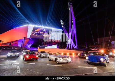 Stuttgart, Deutschland. 08. Juni 2023. Auf dem bunt beleuchteten Porscheplatz stehen während der feierlichen Veranstaltung, bei der 75 Jahre Porsche-Sportwagen gefeiert werden, verschiedene Porsche-Fahrzeuge. Kredit: Christoph Schmidt/dpa/Alamy Live News Stockfoto