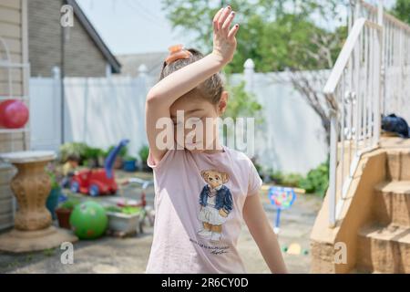 Süßes junges Mädchen, das an einem sonnigen Tag im Garten spielt Stockfoto