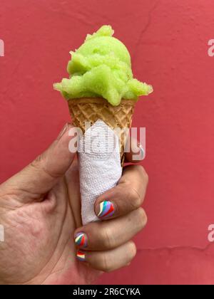 Hand mit Nagel Art Maniküre Spiraldesign mit einer Eiskrem-Dose mit einer Kugel Limettengrün-Sorbet Stockfoto