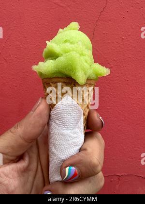 Hand mit Nagel Art Maniküre Spiraldesign mit einer Eiskrem-Dose mit einer Kugel Limettengrün-Sorbet Stockfoto