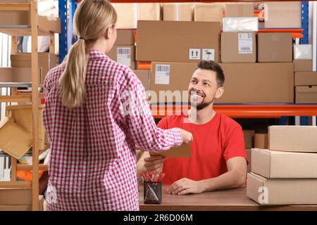 Frau, die ein Paket von einem Mitarbeiter der Post erhält Stockfoto