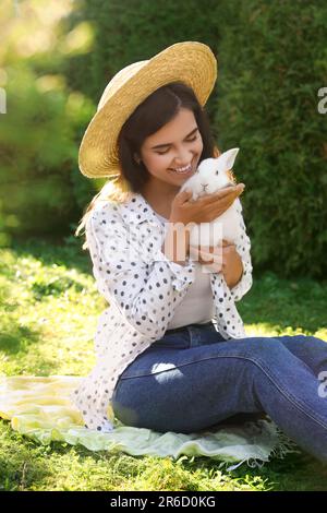 Glückliche Frau mit niedlichem Kaninchen auf grünem Gras draußen Stockfoto