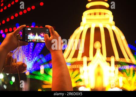 Asiatische männliche Touristen, die ein Handy halten, machen ein Foto im Wat Phra Pathom Chedi Tempel. Stockfoto