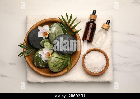 Flache Liegezusammensetzung mit verschiedenen Spa-Produkten und Blumen auf weißem Marmortisch Stockfoto