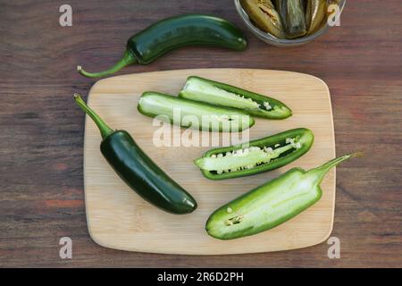 Frische und eingelegte grüne Jalapeno-Paprika auf Holztisch, flach liegend Stockfoto