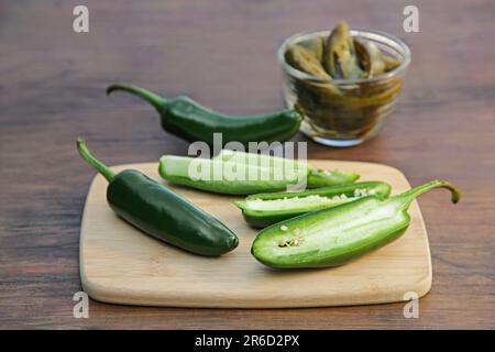 Frische und eingelegte grüne Jalapeno-Paprika auf Holztisch, Nahaufnahme Stockfoto