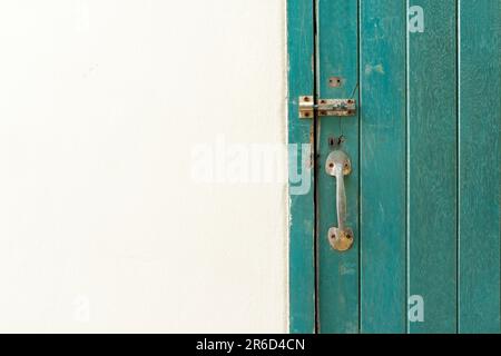 Geschlossenes Vorhängeschloss hängt an der grünen Holztür und -Wand. Stockfoto