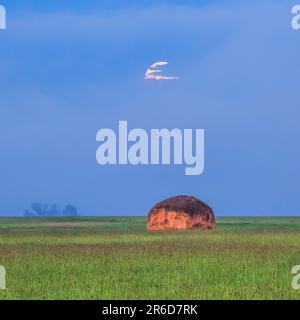 Vollmonduntergang im Nebel über einem Heuhaufen auf einer Wiese bei avon, montana Stockfoto