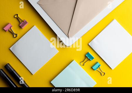 Flache Lage aus schwarzen Stiften, Umschlag und weißem Papier mit Kopierbereich auf gelbem Hintergrund. Schulmaterial, Schreiben, Malen, Zeichnen, Lernen, Schule Stockfoto
