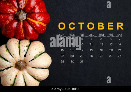 Oktober 2023 Kalender und Kürbisse auf schwarzem Papphintergrund. Stockfoto