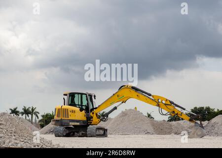 Gelber Hydraulikbagger mit verlängertem Löffel auf einer Deponie in Süd-Florida, USA. Stockfoto