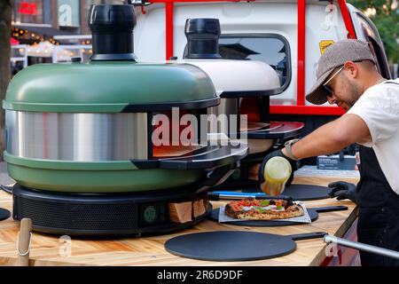 Ein Koch trinkt bei einer CG Pizza Pop-up-Pizzaveranstaltung Olivenöl auf eine neopolitanische Pizza, die in einem Gozney Dome Portable Pizza-Ofen zubereitet wird. Stockfoto