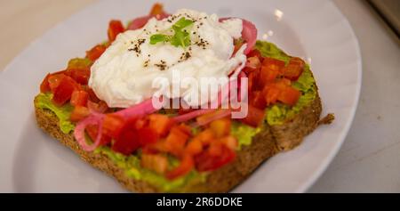 Avocado und Eiertoast mit eingelegten Zwiebeln und Tomaten Stockfoto