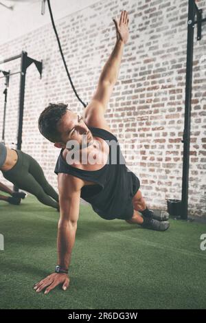 Man kann nie zu beschäftigt sein, um an sich selbst zu arbeiten. Ein Mann, der die seitliche Planke in der Turnhalle macht. Stockfoto