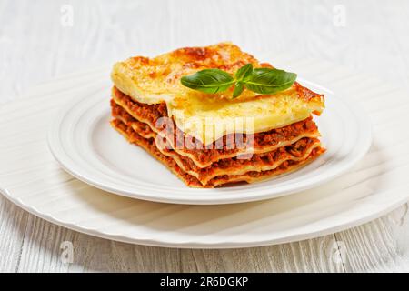 Portion Lasagne al forno, italienische Rinderlasagne mit Rinderhack, Marinara-Sauce, Nudelnudeln und Ricotta-Käse auf weißem Teller auf weißem w Stockfoto