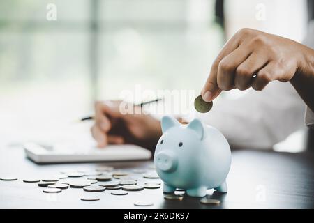 Eine Frau legt Geld ins Schweinchen, um Geld zu sparen, Vermögen und Finanzkonzept. Stockfoto