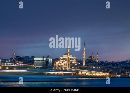 Lange Sicht auf Istanbul in der Dämmerung mit Booten, die am Bosporus-Kanal und der Moschee vorbeifahren. Malerischer Blick auf Istanbul in der Türkei mit Galata-Brücke bei Nacht. Stockfoto