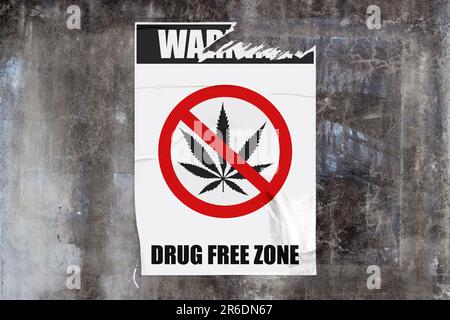 Durchgehende Wand aus verwittertem Beton mit einem zerrissenen weißen Poster in der Mitte, auf dem ein Schild mit der Meldung „Warnung - drogenfrei z Stockfoto