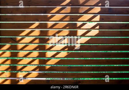 Horizontale Holzbretter mit diagonalem Sonnenlichtmuster, abstrakte Tapetenstruktur Stockfoto