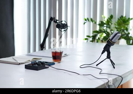 Mikrofone, Verstärker und eine Tasse schwarzen Tee auf dem Tisch, bereit für die Aufnahme von Podcasts Stockfoto