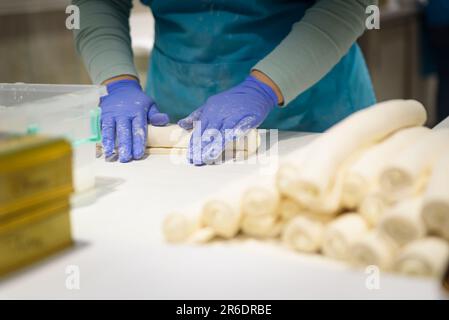 Nahaufnahme von Händen, die traditionellen türkischen Honig in einer Bäckerei zubereiten, die den Teig rollt. Die Türkei ist berühmt für ihre Süßigkeiten Stockfoto