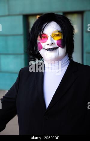 Ein glücklicher und lächelnder männlicher Cosplayer mit Gesichtsfarbe und Perücke in einem Anime-Kostüm auf einer UK Comic Con Stockfoto