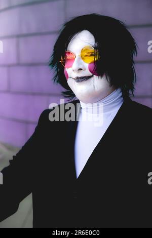 Ein glücklicher und lächelnder männlicher Cosplayer mit Gesichtsfarbe und Perücke in einem Anime-Kostüm auf einer UK Comic Con Stockfoto
