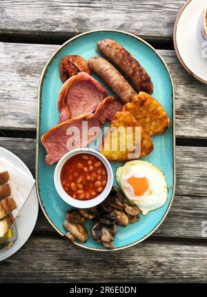 Flach liegendes Essen Bild eines kompletten englischen frittierten Frühstücks mit Speck, Würstchen und Eiern Stockfoto