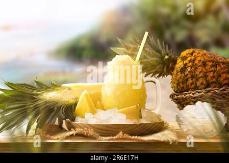 Ananassuppe mit Früchten auf einem Holztisch draußen mit Naturhintergrund. Vorderansicht. Horizontale Zusammensetzung. Stockfoto
