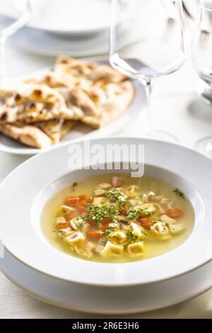 Hühnerbrühe oder Suppe mit Gemüse und kleinen italienischen Pasta auf einem Tisch serviert. Stockfoto