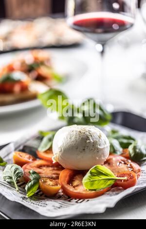 Italienischer leichter Sommer-Caprese-Salat mit Arschloch-Büffelmozzarella, Kirsche und Tomaten in Scheiben und frischem Basilikum. Stockfoto