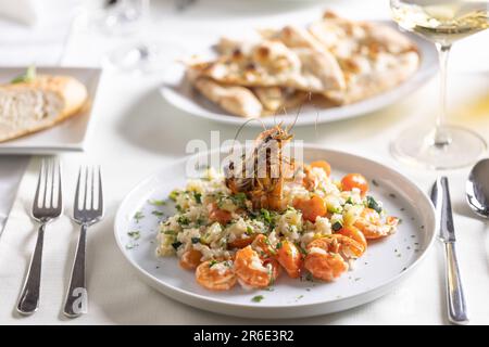 Ausgefallene Garnelen und Risotto mit Zucchini auf einem Tisch im Restaurant. Stockfoto