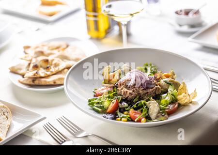 Salat mit Thunfisch, Gemüse, Zwiebeln, Avocado und Kirschtomaten auf einem Tisch serviert. Stockfoto
