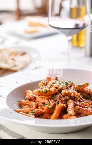 Penne alla arrabiata serviert mit Weißwein in einem Restaurant. Stockfoto