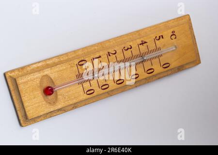 Raumthermometer auf einem Holzsockel, Nahaufnahme auf weißem Hintergrund. Grad Celsius. Stockfoto