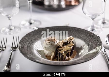 Schokoladen-Brownies mit Karamell und Schlagsahne, wunderschön auf einem Teller serviert. Stockfoto