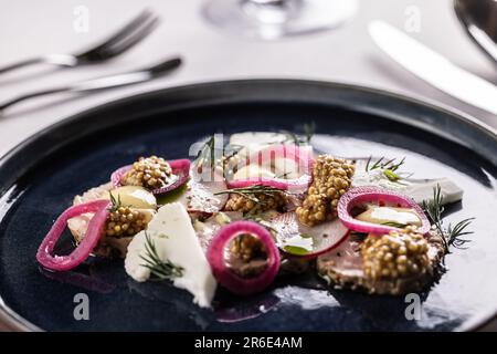 Entenpastete serviert mit roten Zwiebeln, Blumenkohl, Radal und Senfsamen. Stockfoto