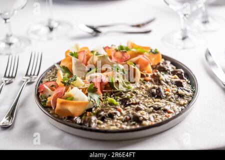 Teller voller cremiger Aromorio-Reis-Pilz-Risotto mit Streifen von Wurzelgemüse. Stockfoto