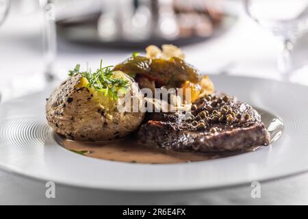 Gut gemachtes Rib-Eye-Steak auf einem Teller mit gebackener Kartoffel und Petersilie als Dekoration. Stockfoto