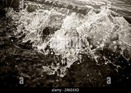 Eine kleine Welle stürzt am Strand eines Sees ab. Stockfoto