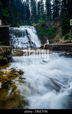 Eine Frau, die an den Ousel Falls in Big Sky, Montana sitzt Stockfoto